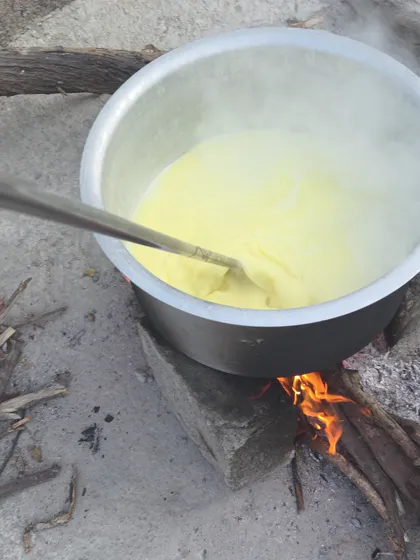 Butter slow-cooking into ghee in a pot over a wood fire at our farm